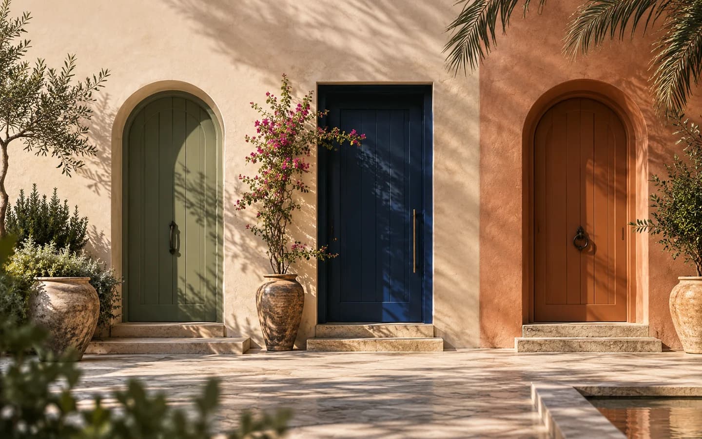 Three distinct sage, blue and terracotta doorways in a sunlit courtyard.