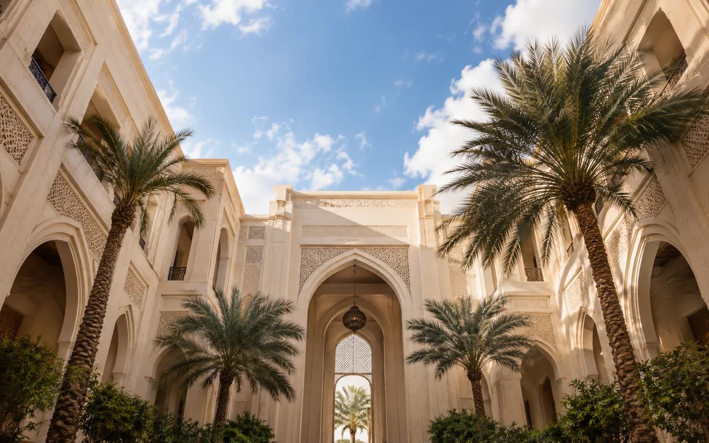 Cream stone architecture frames an open blue sky above a Dubai courtyard.