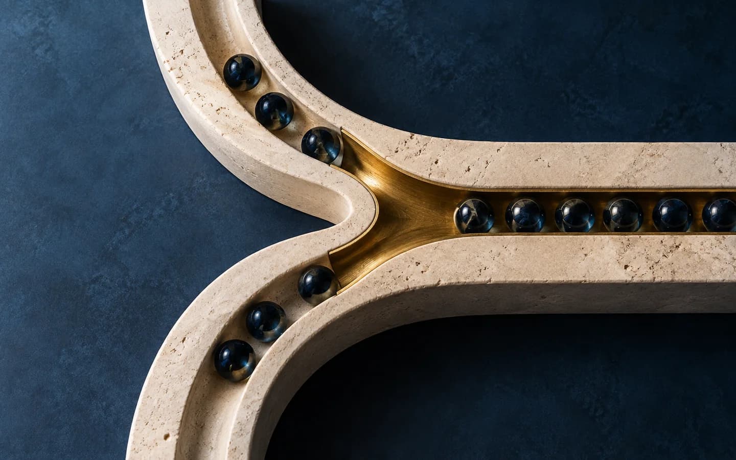 Two limestone channels bring glass marbles into one brass-lined channel.